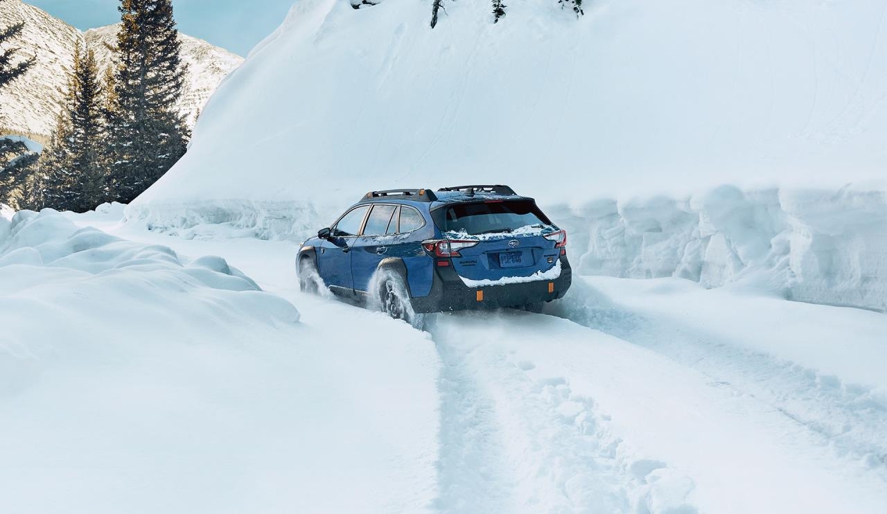 Vue 3/4 arrière du Subaru Outback 2024 roulant dans de la neige épaisse.