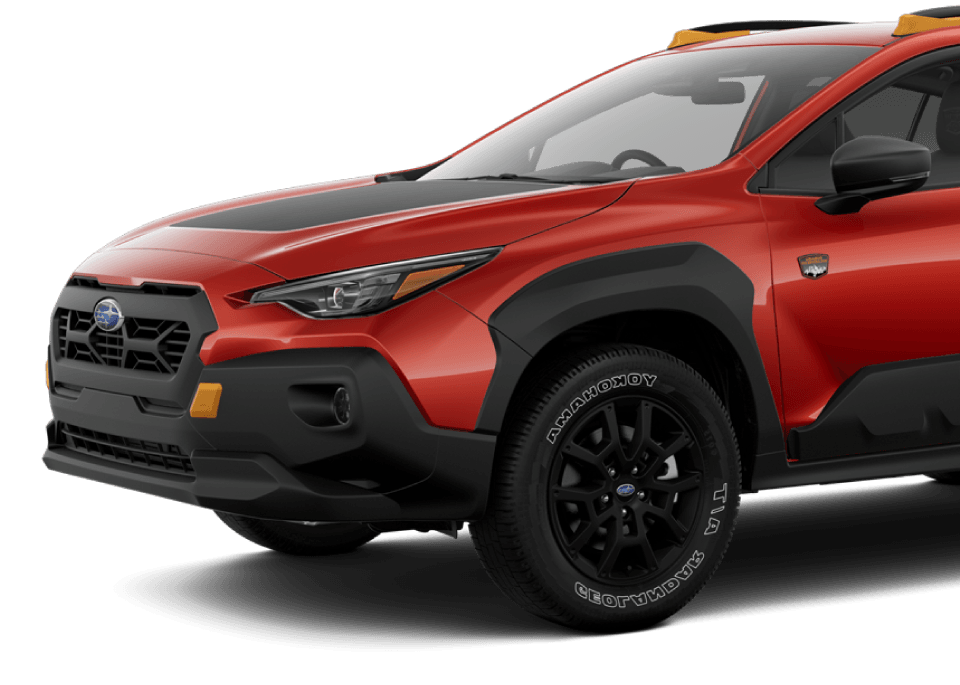 Vue latérale du Subaru Crosstrek Wilderness 2025 rouge, avec garde-boue noirs et logo Wilderness sur l’aile.