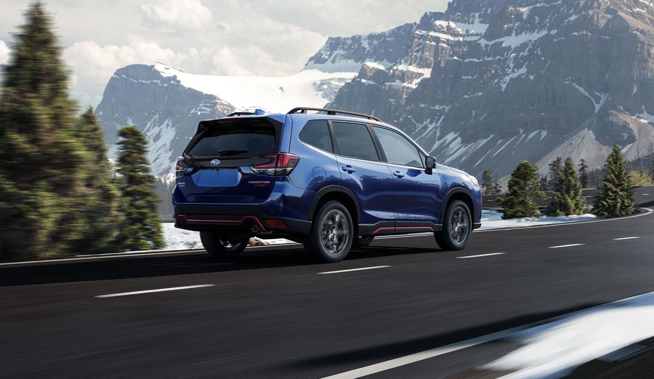 Vue 3/4 arrière du Subaru Forester 2023 bleu roulant sur une route.