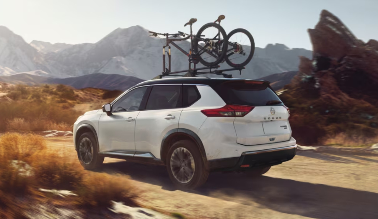 vue latérale arrière d'une Nissan Rogue 2024 transportant des vélos sur un sentier de campagne