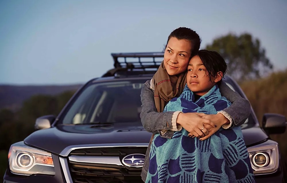 Mère serrant son enfant fort à l'avant d'une Subaru.