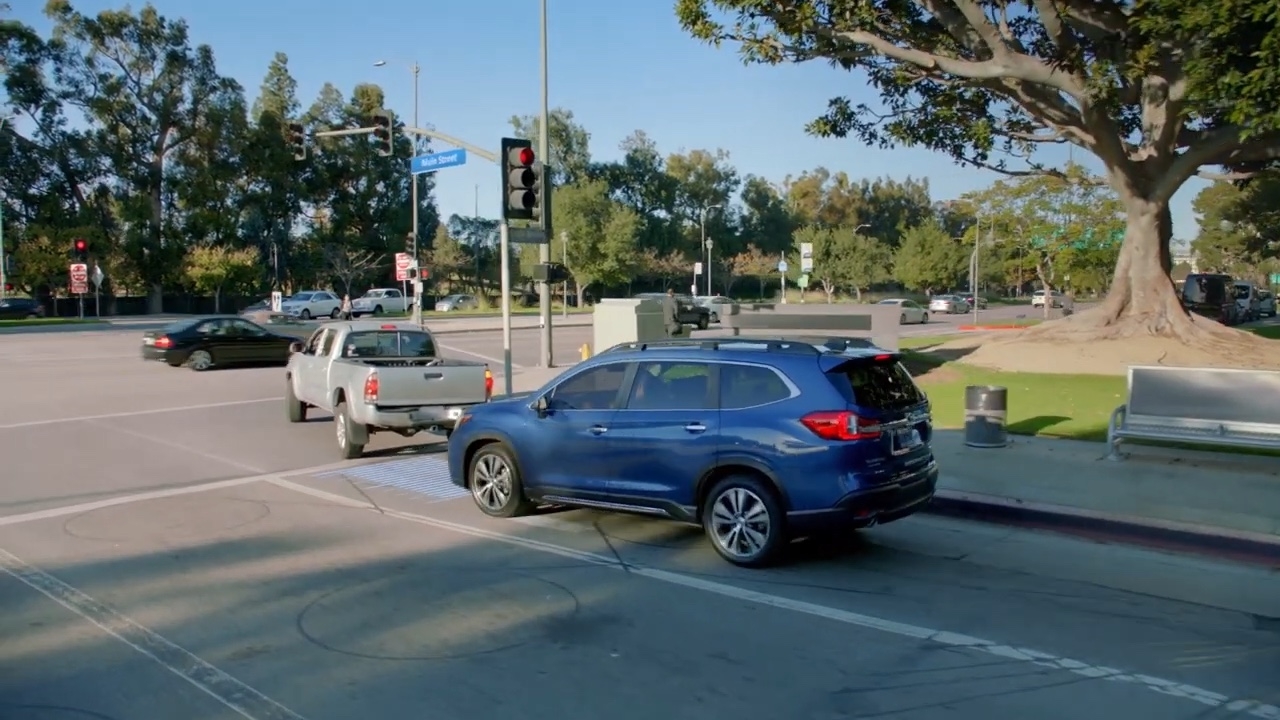 Subaru bleu à l’arrêt derrière une camionnette grise à une lumière rouge, illustrant la gestion de l’accélération précollision en milieu urbain.