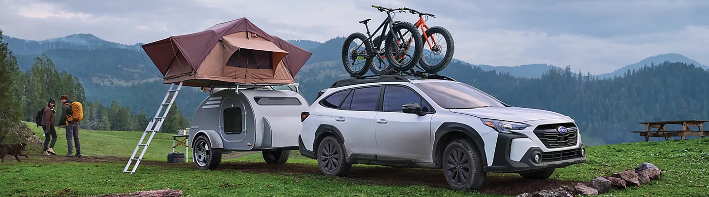 vue latérale avant d'une Subaru Outback 2025 attaché à une roulotte dans un champ