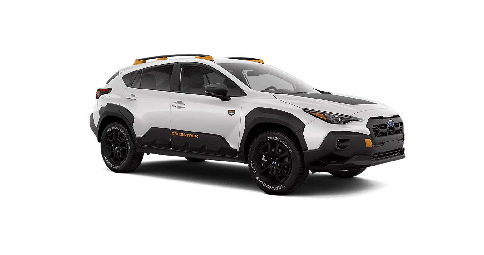 Vue trois quarts avant du Subaru Crosstrek Wilderness 2025 blanc sur fond transparent, avec garnitures noires contrastantes, jantes noires, pneus tout-terrain Yokohama et accents orange sur le toit et les pare-chocs.