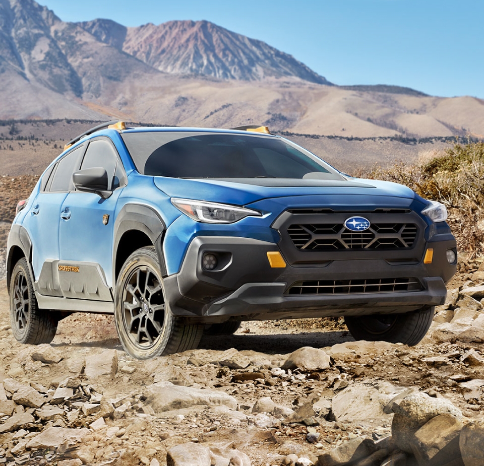 Subaru Crosstrek Wilderness 2025 bleu foncé vue de face sur route, avec pare-chocs noir et accents cuivrés visibles.